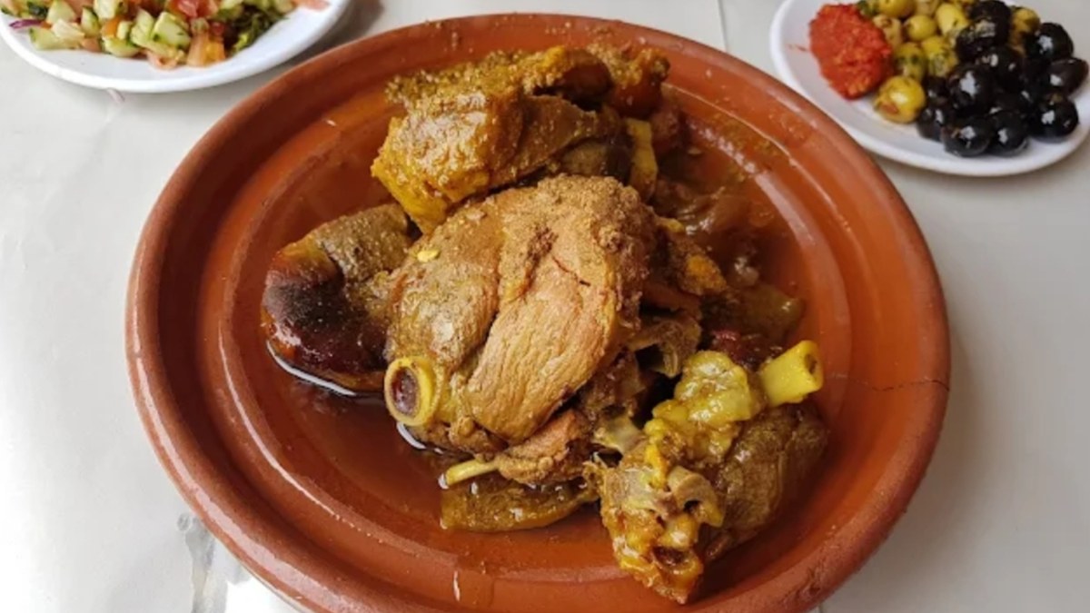 Moroccan tagine with olives and salad on a restaurant table